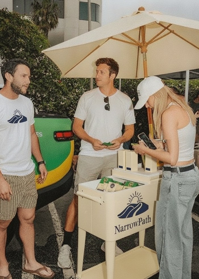 Guests sampling NarrowPath gummies at an umbrella-shaded event cart