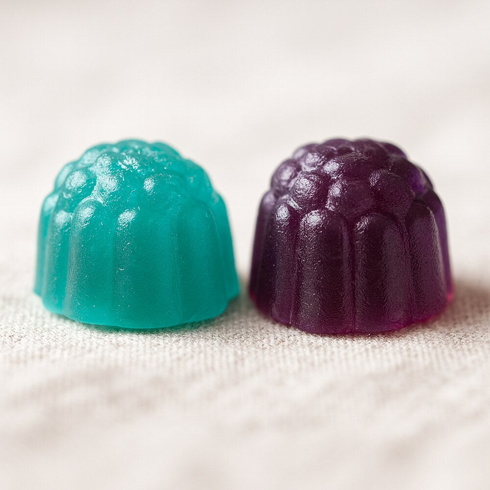 Macro photograph of two Natures Relax berry-shaped gummies, teal and violet, on linen