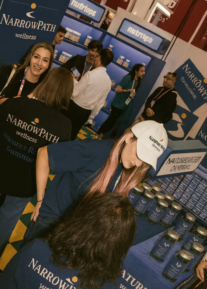The NarrowPath wellness booth at a trade show, team in branded tees and caps